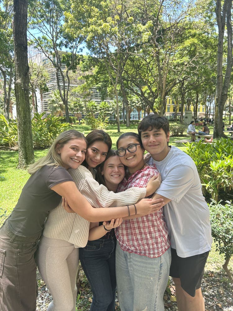 Grupo de jóvenes sonriendo y abrazándose en un parque, representando el apoyo comunitario y el bienestar emocional en la Fundación Ayúdate.